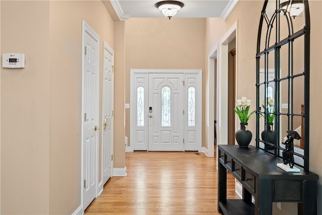 foyer with hardwood / wood-style floors, a healthy amount of sunlight, and crown molding