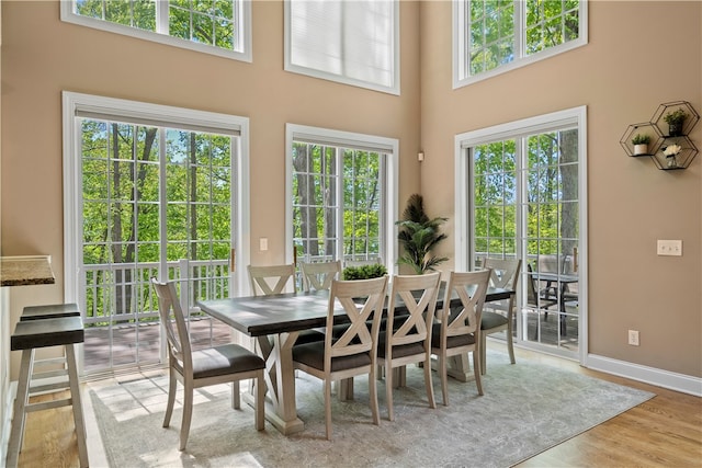 dining space featuring light wood-type flooring and a towering ceiling