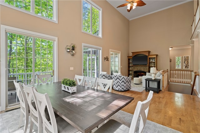 dining area with light wood-type flooring, a towering ceiling, and a wealth of natural light