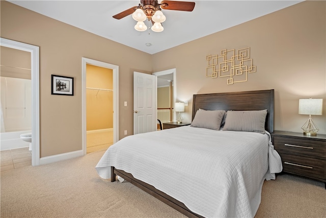 bedroom featuring ceiling fan, connected bathroom, a closet, a spacious closet, and light carpet