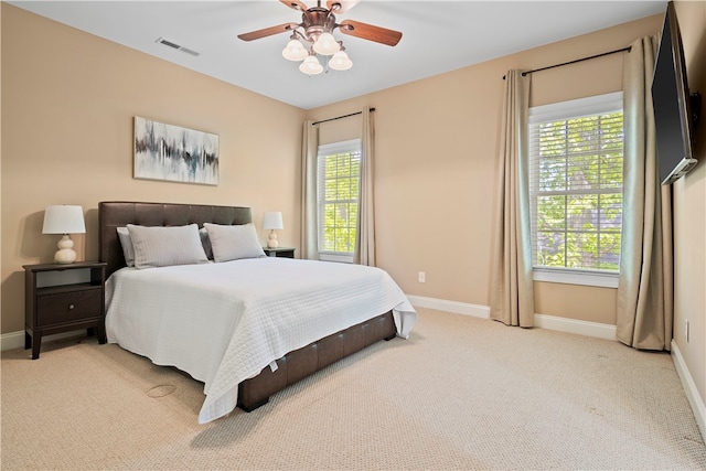 carpeted bedroom featuring multiple windows and ceiling fan