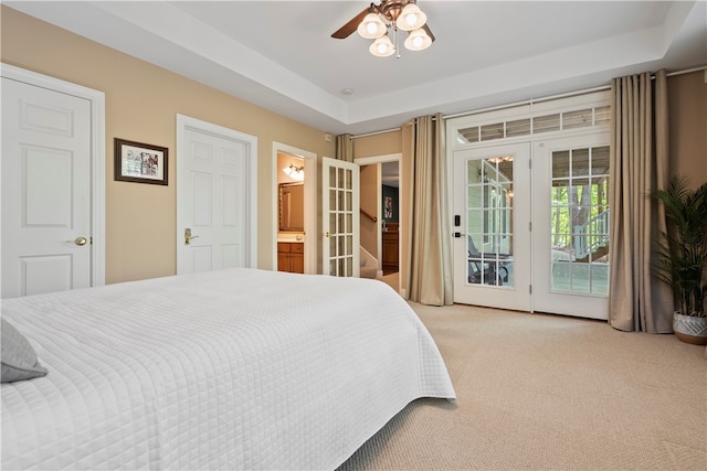 carpeted bedroom with access to outside, a raised ceiling, ensuite bathroom, and ceiling fan