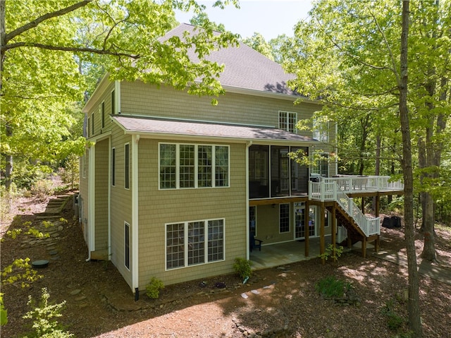 back of property with a sunroom, a wooden deck, and a patio area