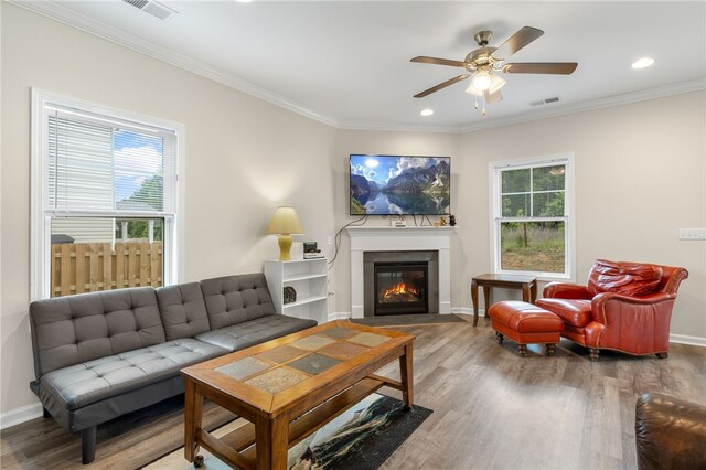 living room featuring wood-type flooring, ornamental molding, and a wealth of natural light