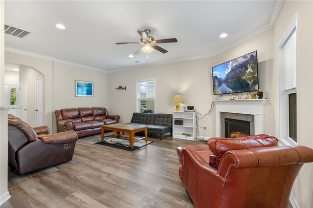 living room featuring wood-type flooring, crown molding, and ceiling fan