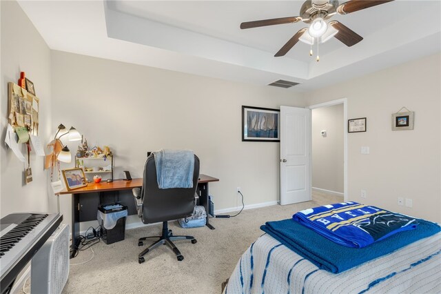 carpeted bedroom with ceiling fan and a raised ceiling