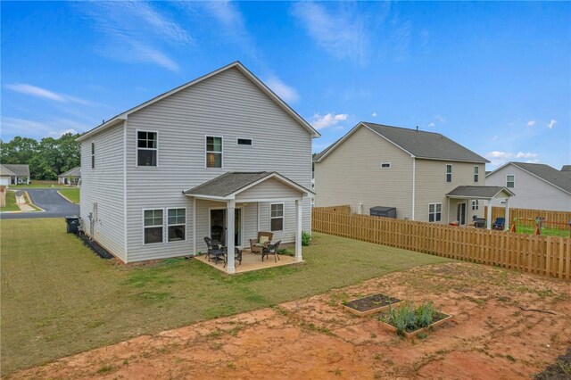 back of house with a lawn and a patio