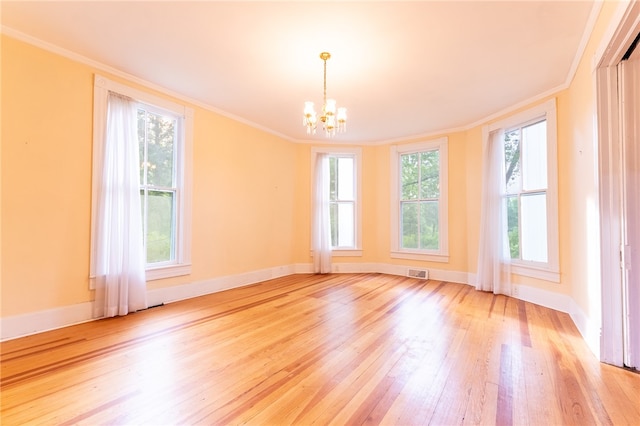 spare room featuring crown molding, light hardwood / wood-style floors, and a chandelier