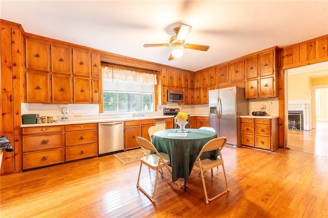 kitchen featuring appliances with stainless steel finishes, ceiling fan, light hardwood / wood-style flooring, and tasteful backsplash