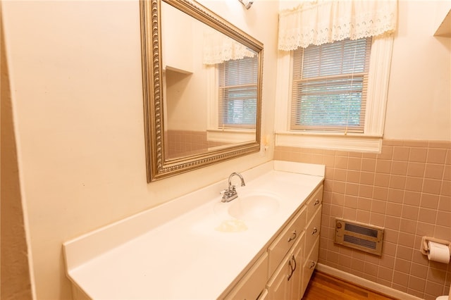 bathroom featuring heating unit, tile walls, hardwood / wood-style flooring, and vanity