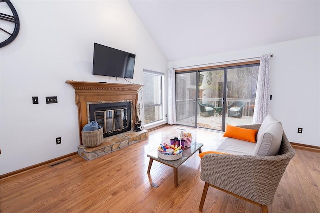 living room featuring wood-type flooring, high vaulted ceiling, and a fireplace