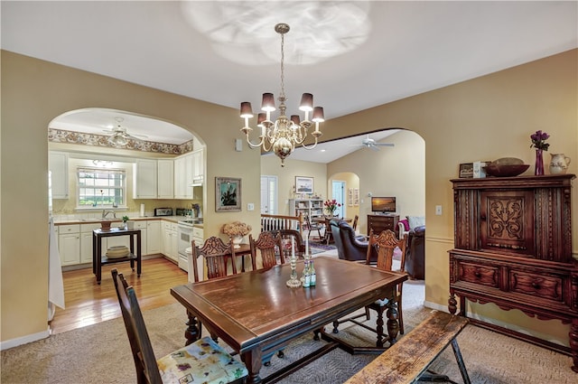 dining room with ceiling fan with notable chandelier and light hardwood / wood-style flooring