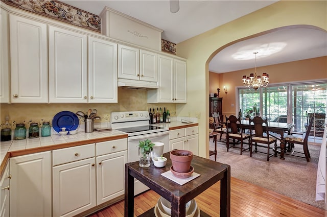 kitchen featuring light hardwood / wood-style flooring, tile countertops, hanging light fixtures, and white electric range