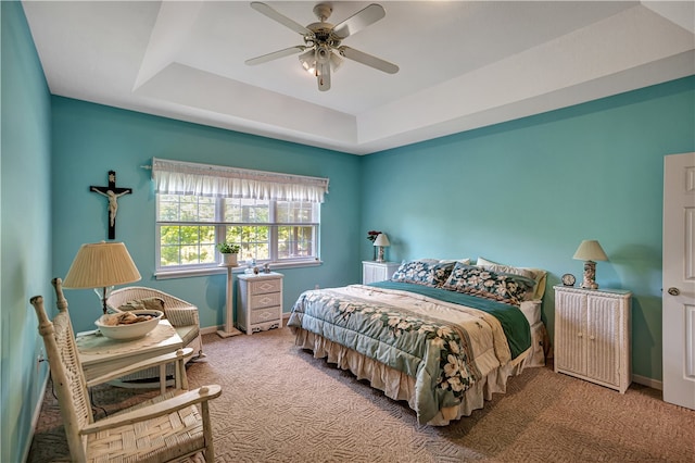 carpeted bedroom featuring a tray ceiling and ceiling fan