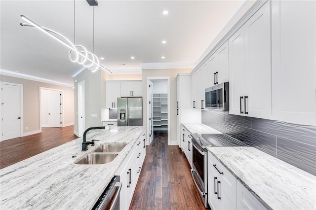 kitchen with sink, white cabinetry, light stone counters, decorative light fixtures, and stainless steel appliances