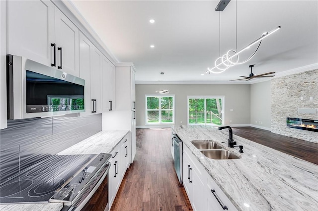 kitchen with sink, crown molding, appliances with stainless steel finishes, light stone counters, and white cabinets