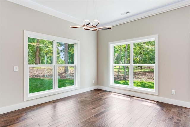 empty room featuring hardwood / wood-style flooring, crown molding, and a notable chandelier