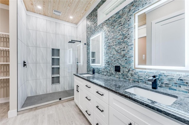 bathroom featuring tasteful backsplash, tiled shower, vanity, and hardwood / wood-style floors