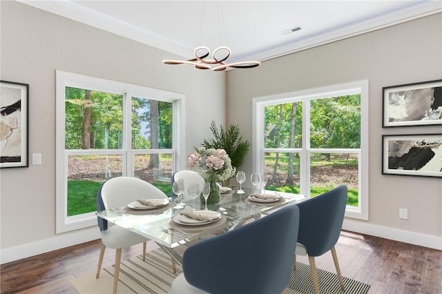 dining room featuring an inviting chandelier, ornamental molding, and dark hardwood / wood-style floors