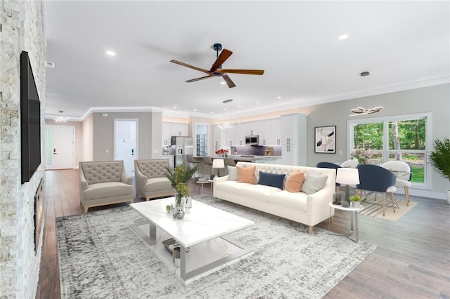 living area with recessed lighting, baseboards, light wood-style flooring, ornamental molding, and ceiling fan with notable chandelier