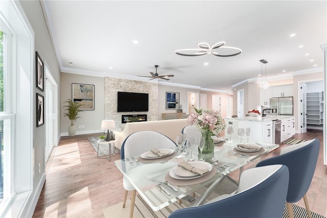 dining area with crown molding, a large fireplace, and light wood-type flooring