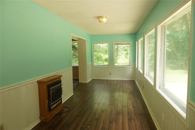 unfurnished sunroom featuring heating unit and plenty of natural light