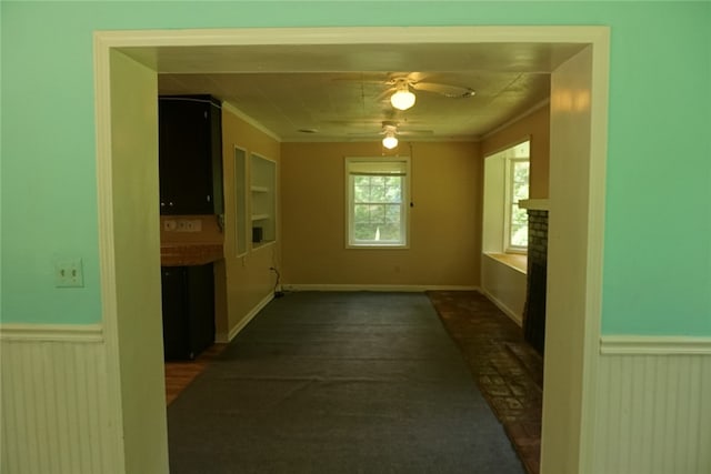 interior space featuring ceiling fan, dark colored carpet, a fireplace, and ornamental molding