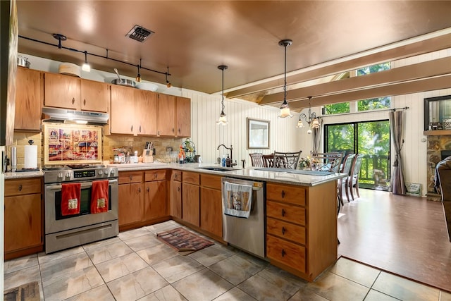 kitchen featuring hanging light fixtures, sink, kitchen peninsula, backsplash, and appliances with stainless steel finishes