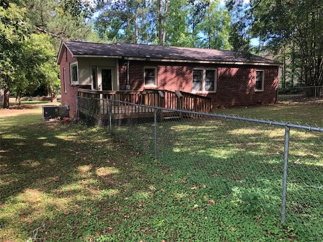 single story home featuring a deck, a front yard, and central air condition unit