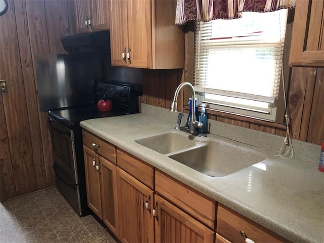 kitchen featuring exhaust hood, black range with electric cooktop, wood walls, and sink