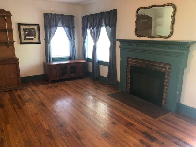 unfurnished living room featuring a fireplace and dark wood-type flooring