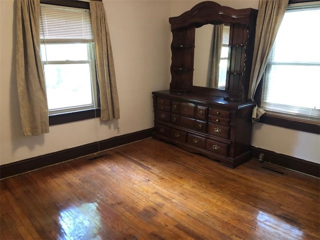 unfurnished bedroom with multiple windows and dark hardwood / wood-style flooring