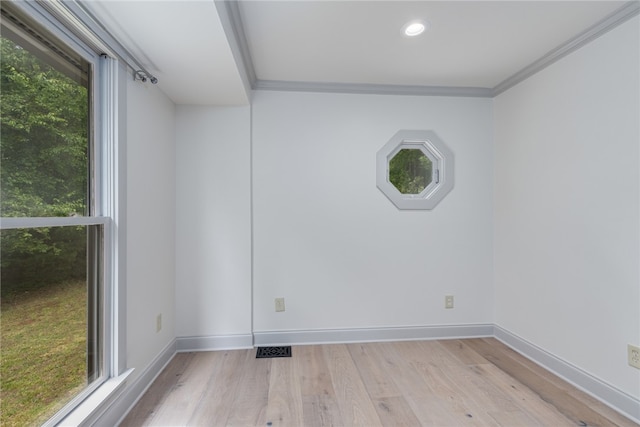 empty room with a wealth of natural light, light hardwood / wood-style floors, and crown molding