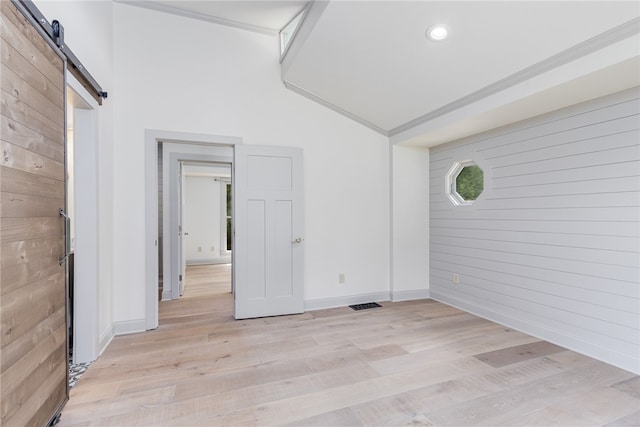 spare room featuring light wood-type flooring, wood walls, and a barn door