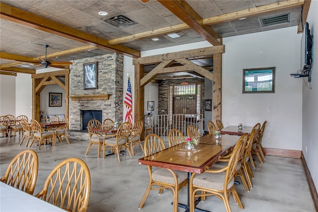 dining area with beam ceiling, concrete flooring, ceiling fan, and a fireplace