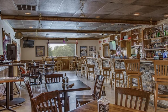 dining area featuring a paneled ceiling, visible vents, and a community bar