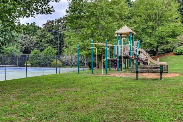 community jungle gym featuring a yard, a tennis court, and fence