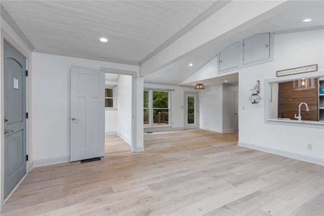 empty room with ornamental molding, lofted ceiling, light hardwood / wood-style floors, and sink