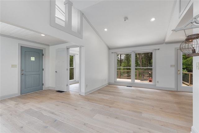 interior space with ornamental molding, light wood-type flooring, and vaulted ceiling