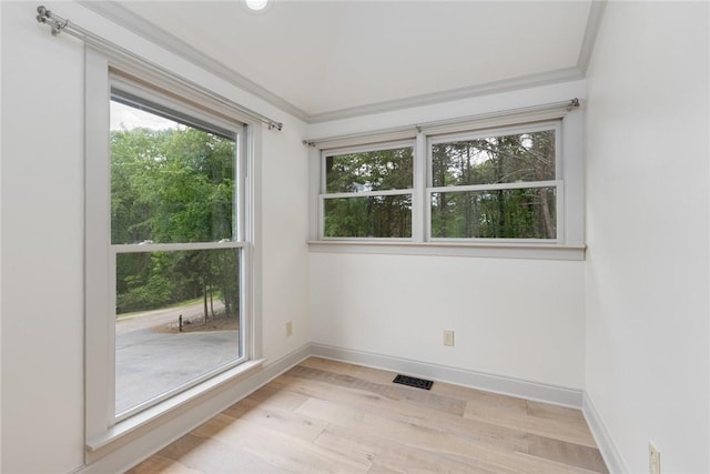 unfurnished room featuring light wood-style floors, visible vents, crown molding, and baseboards