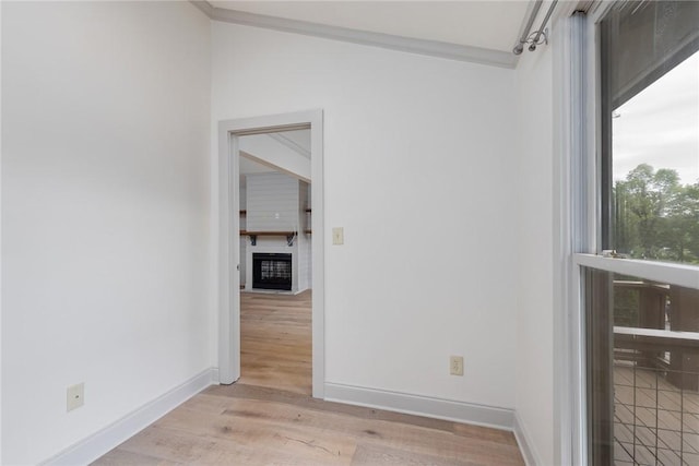 unfurnished room featuring light wood-type flooring, baseboards, and a glass covered fireplace