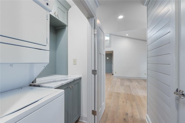 clothes washing area featuring recessed lighting, stacked washing maching and dryer, laundry area, and light wood-style floors