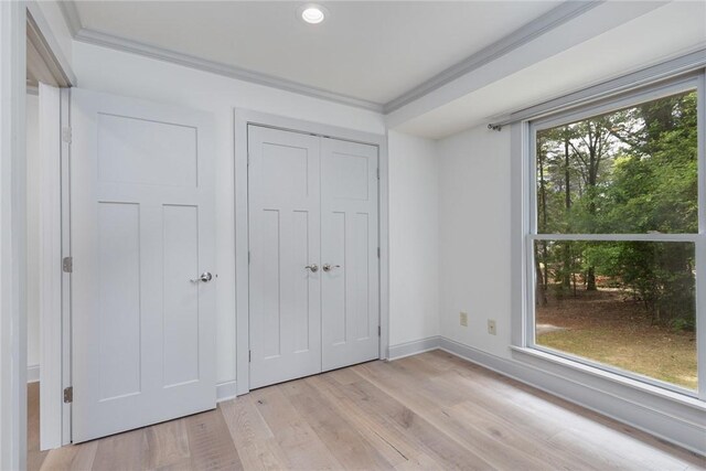 unfurnished bedroom with light wood-style flooring, baseboards, a closet, and ornamental molding