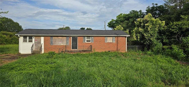 view of front of house with crawl space, brick siding, and fence