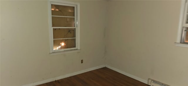 empty room featuring a baseboard heating unit and hardwood / wood-style floors