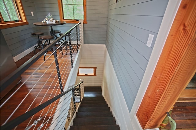 staircase with wood walls and dark wood-type flooring