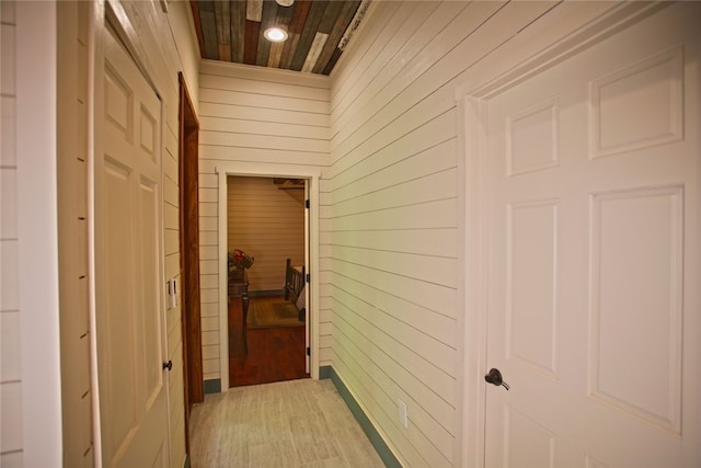 hallway with wood walls, wooden ceiling, and hardwood / wood-style floors