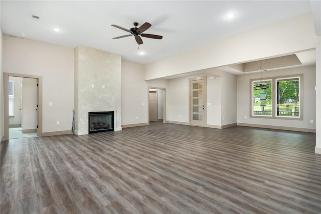 unfurnished living room featuring dark hardwood / wood-style flooring, ceiling fan, and a large fireplace