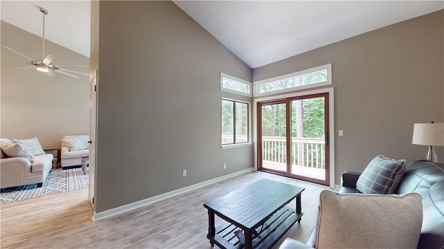 living room with high vaulted ceiling, ceiling fan, and light wood-type flooring