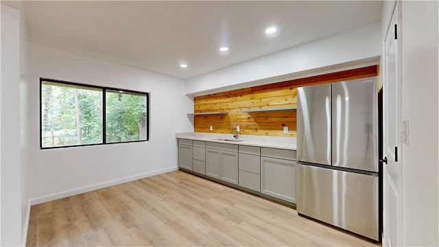 kitchen with gray cabinets, stainless steel fridge, light hardwood / wood-style flooring, and sink